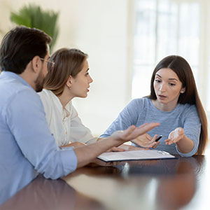 Woman speaking passionately while reviewing a document with two people, workers' compensation mistakes in Maryland.