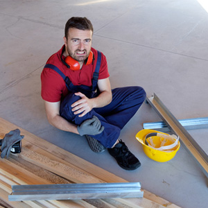 Construction worker injured on the job holding knee, showing worker's compensation in Maryland.
